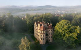 Ein Schloss umgeben von Bäumen bei Sonnenuntergang.