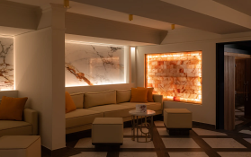 Moderne Lounge mit bequemen Sitzgelegenheiten und beleuchteter Salzwand.